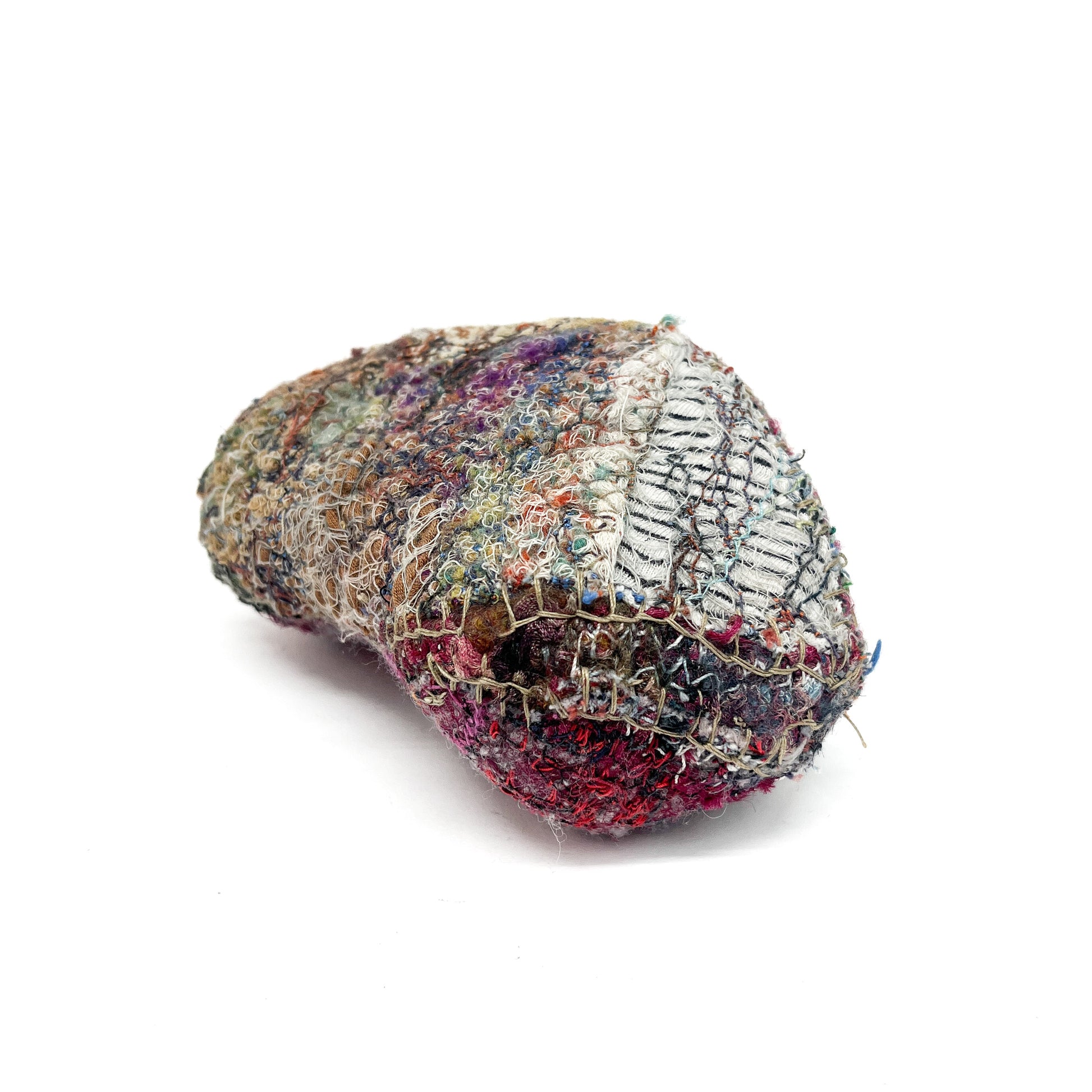 Heavily textured, rounded textile object with layers of colorful stitching and varied fabric