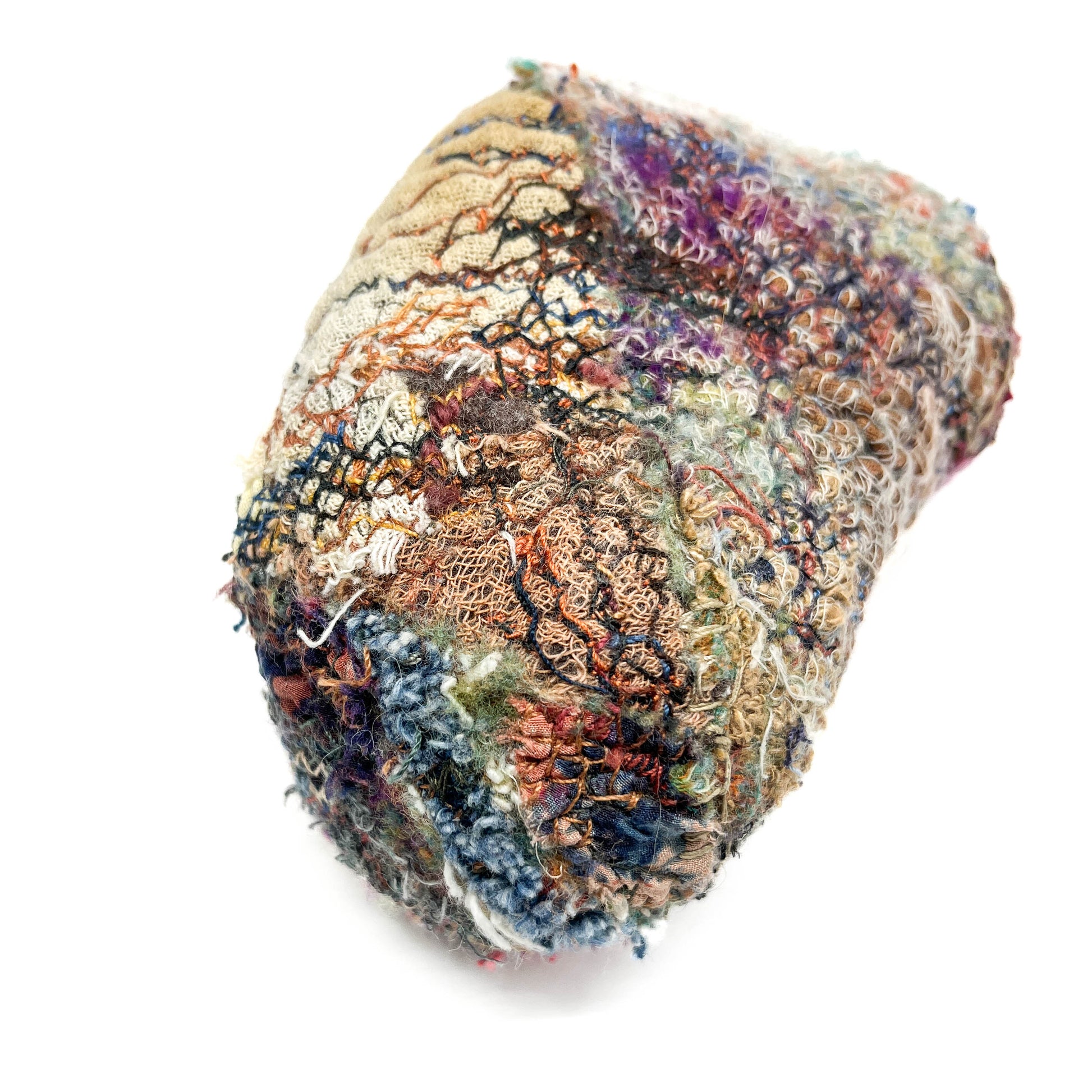 Intricately stitched textile object with rich textures and a blend of diverse threadwork.