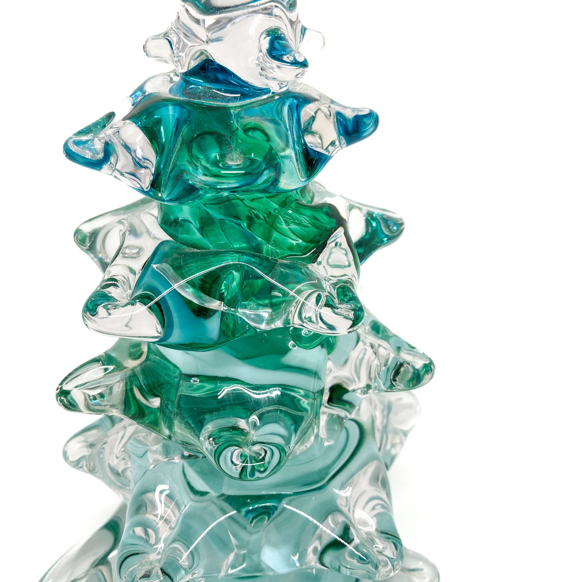 Close up of a large, clear glass Christmas tree with green swirls.