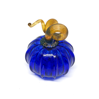A cobalt blue glass pumpkin with a curled, amber-colored stem.