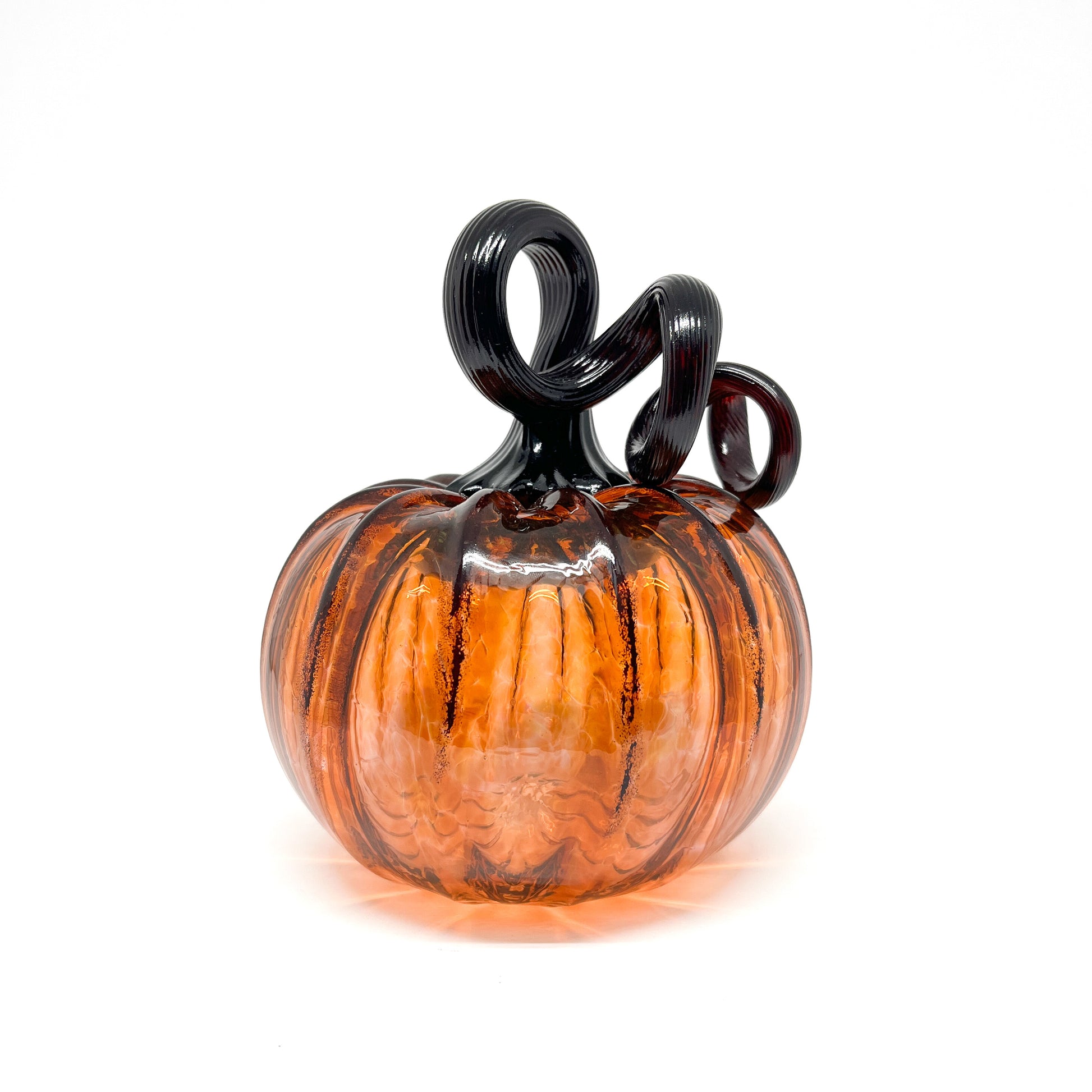 An amber glass pumpkin with a curled, black glass stem.