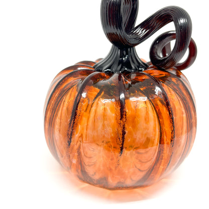 An amber glass pumpkin with a curled, black glass stem.
