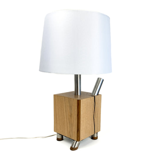 Table lamp with white shade, light wood block base, and metal rods.