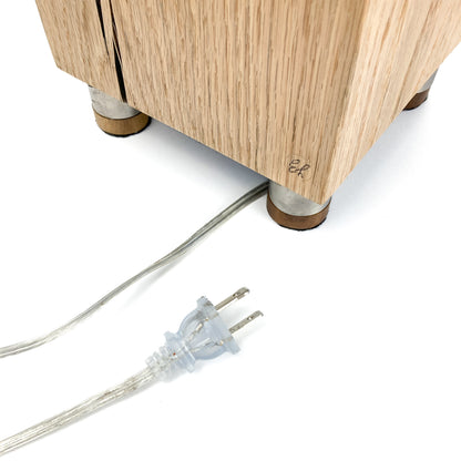 Lamp base detail: light wood block, feet, power cord with plug.