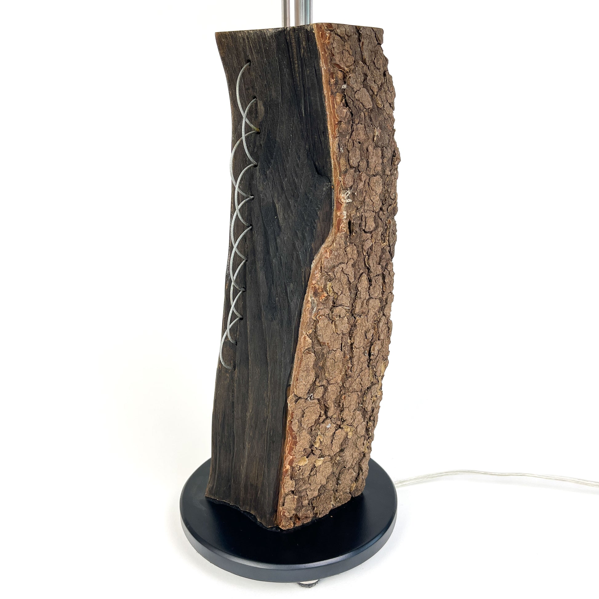 Close-up of a lamp base: textured wood with metal accents, black round base.