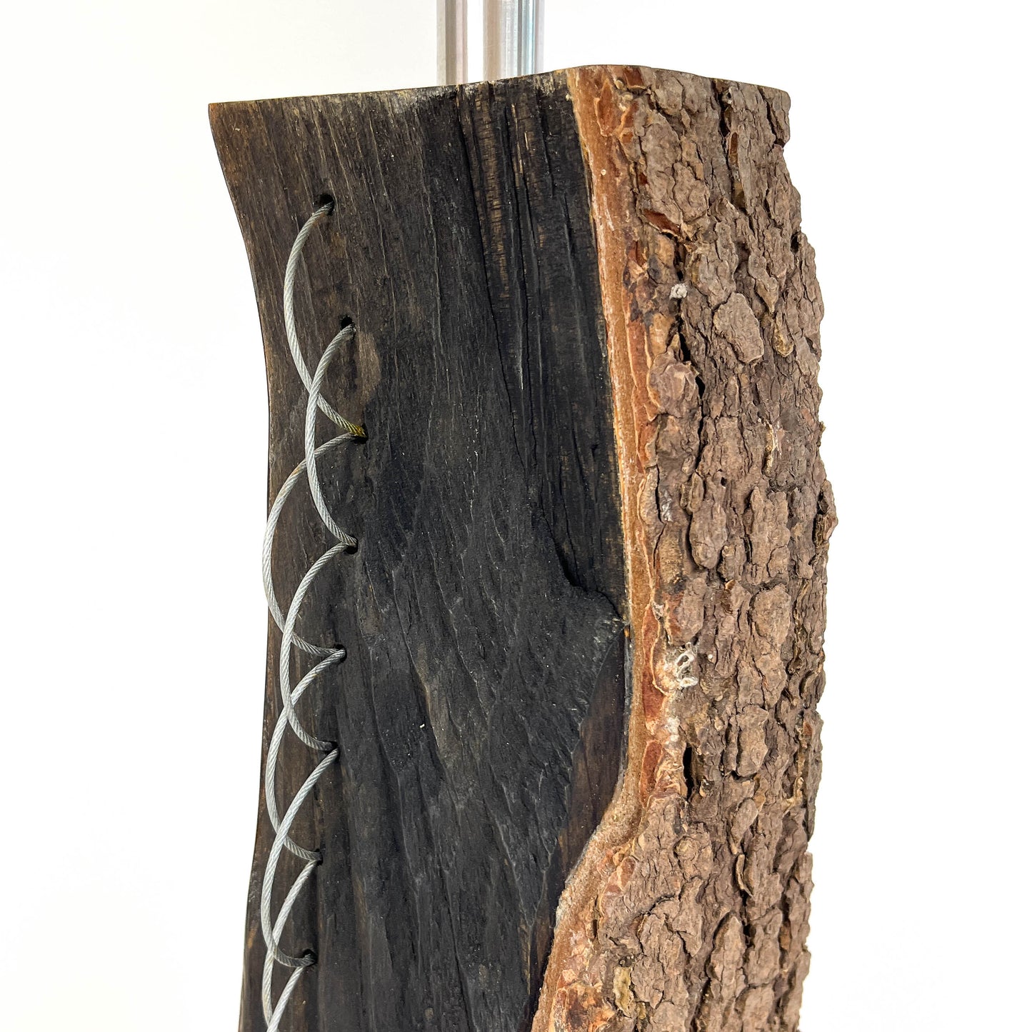Close-up of a lamp base: dark wood with bark texture and metal string detail.