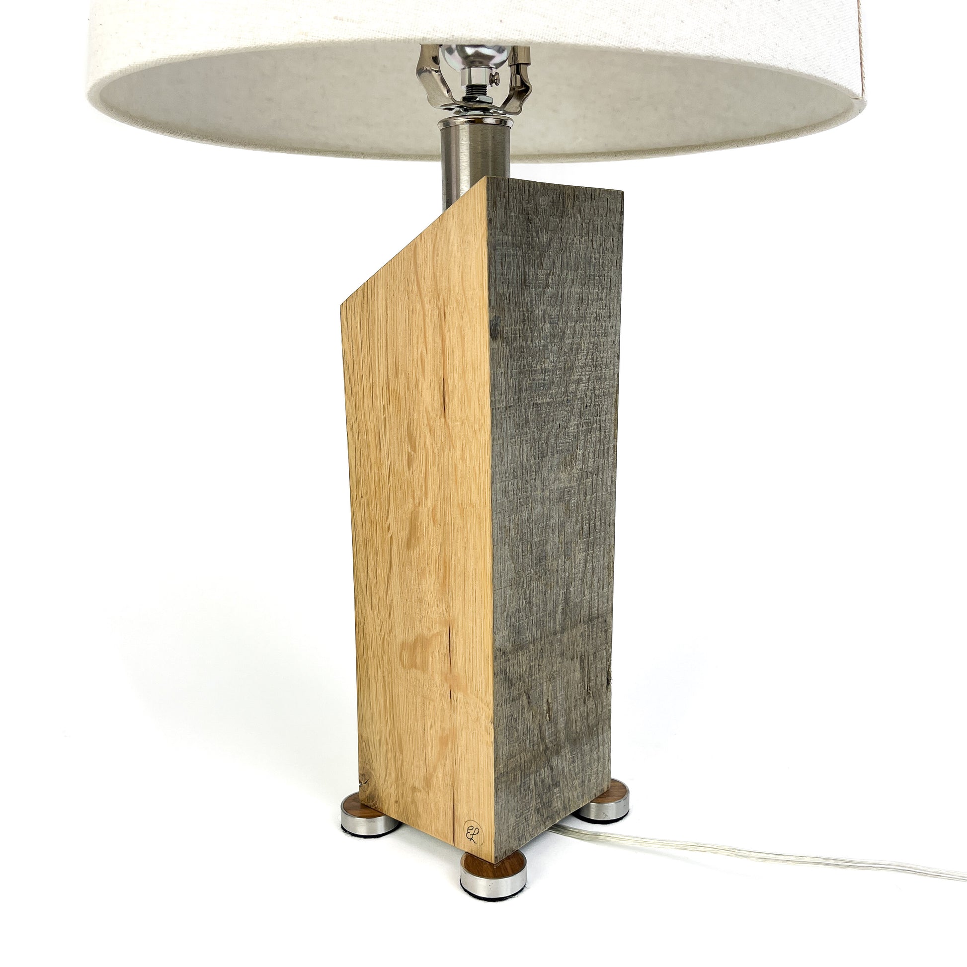 A table lamp with a two-toned wood base, white shade, and small metal feet.