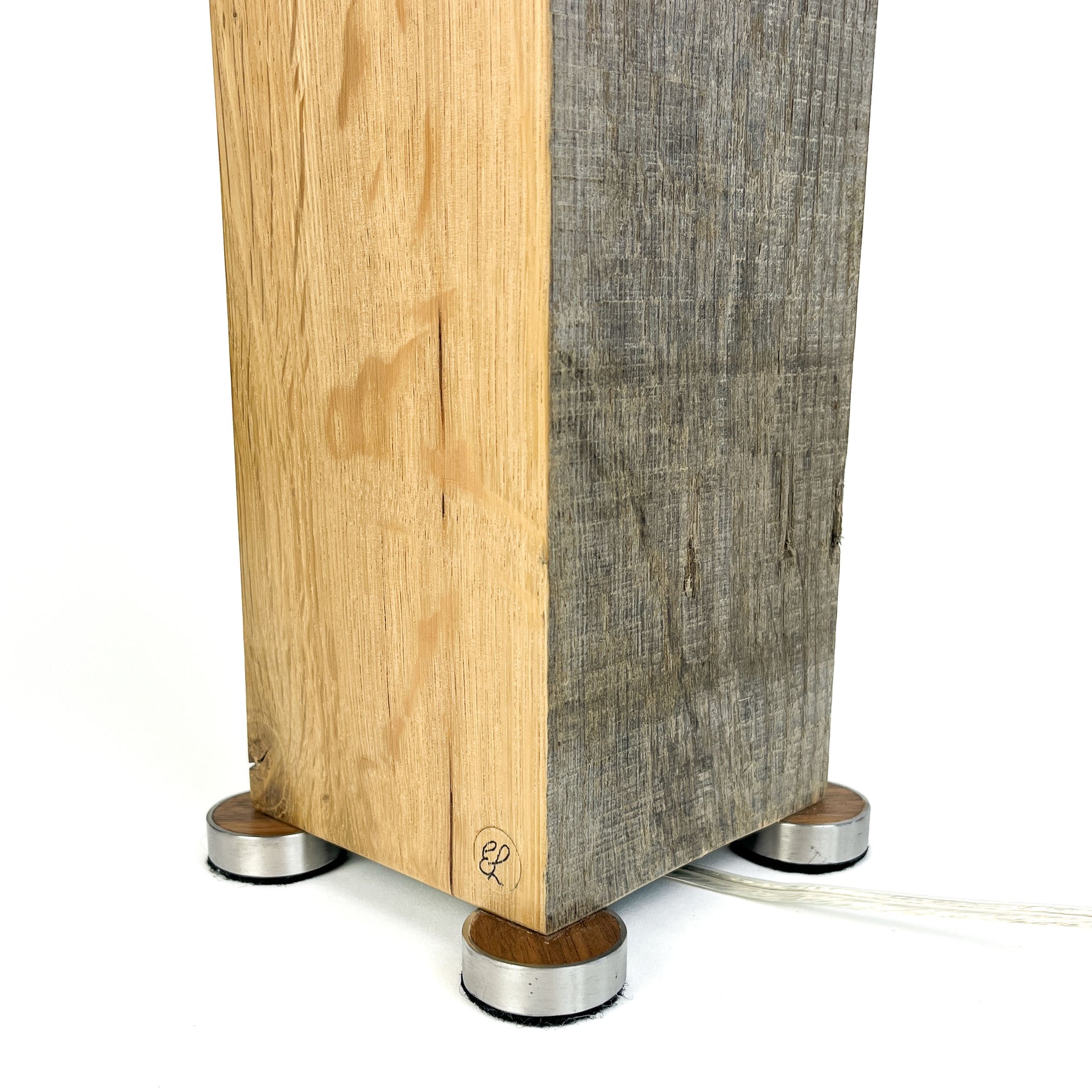 Close-up of a lamp base: two-toned wood block, small metal feet, and power cord.