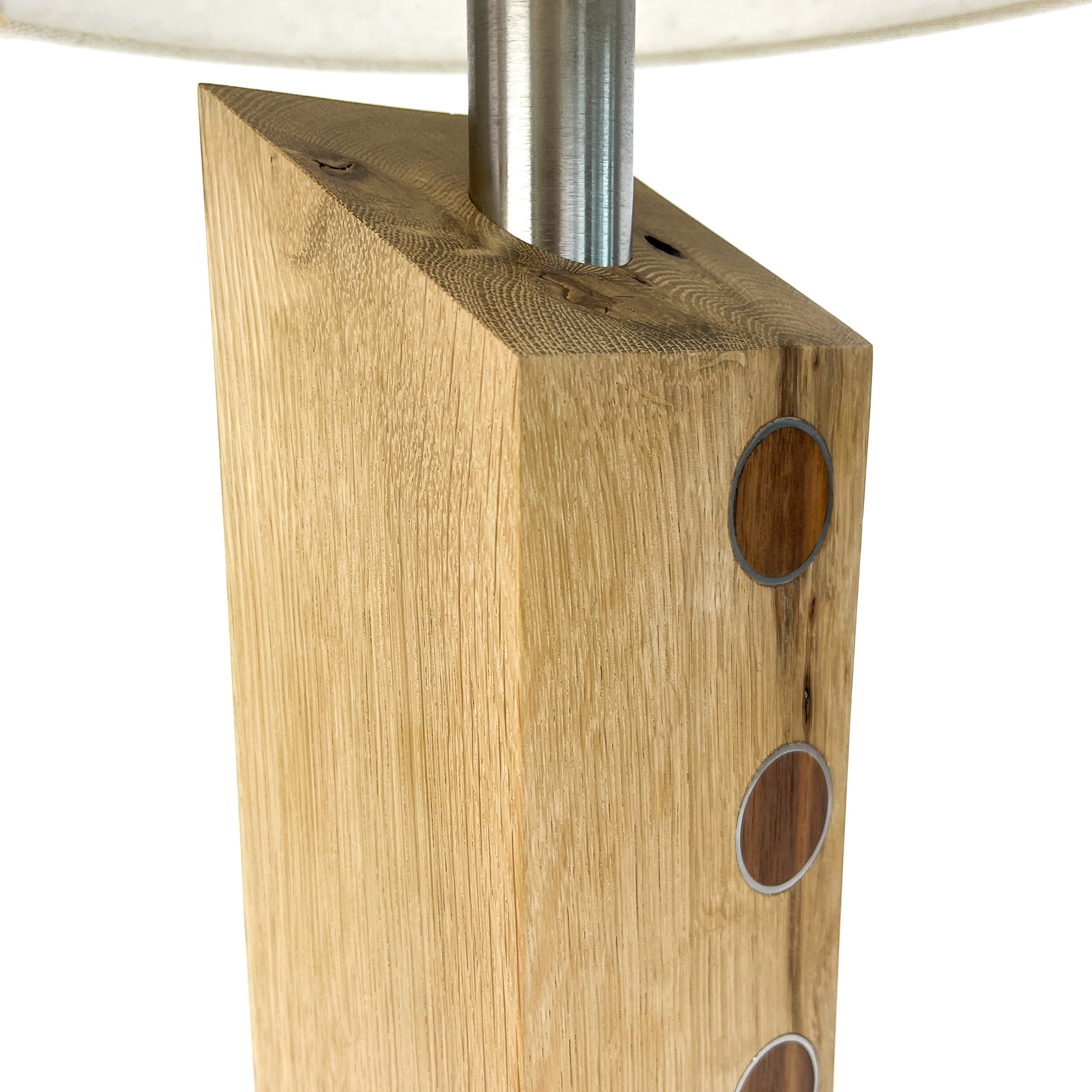 Close-up of a lamp base: light wood block with metal circles and a metal rod.