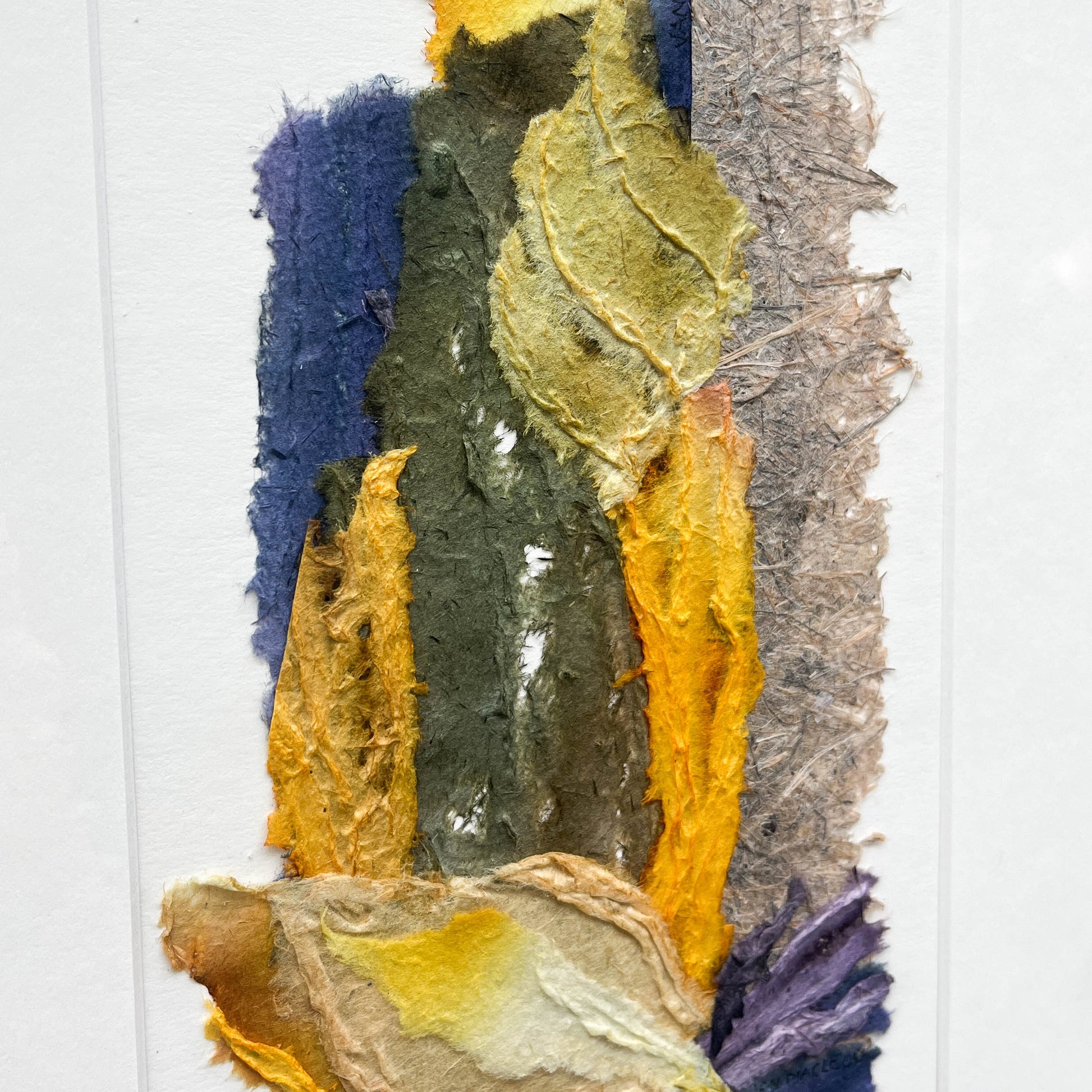 Close-up of abstract textile art showing layered textures and blended hues of yellow, blue, green, brown, and gray.