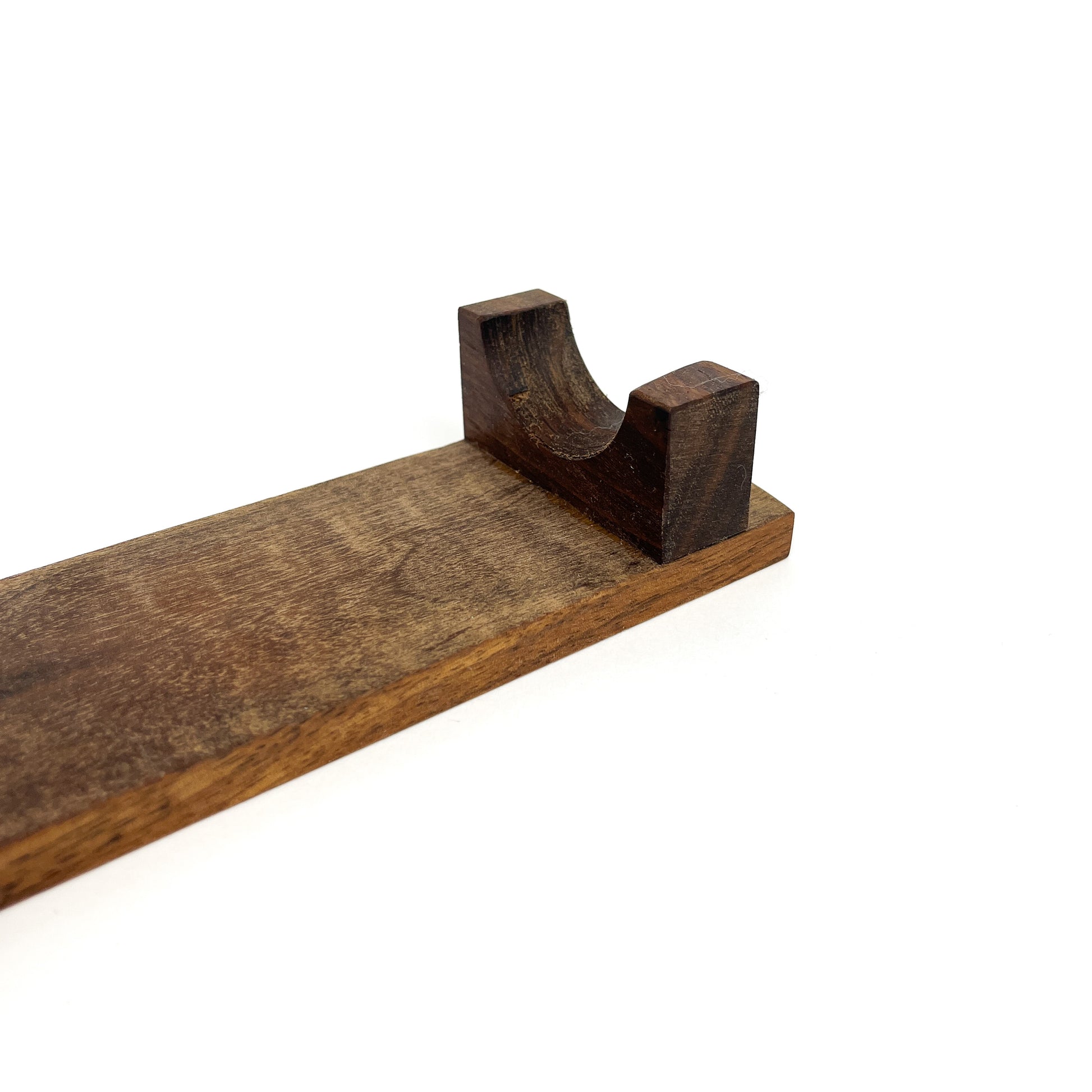 A close-up of a dark wooden French rolling pin stand, showing one of the carved supports. The stand has a visible wood grain.