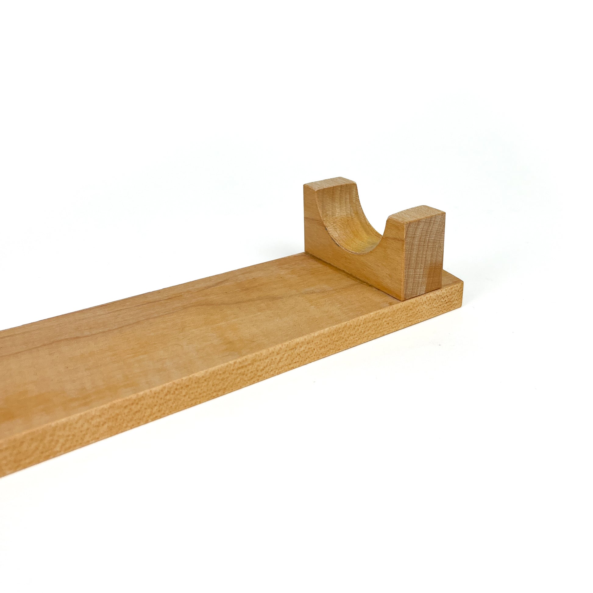 A close-up of a light wooden French rolling pin stand, showing one of the carved supports. The stand has a visible wood grain.
