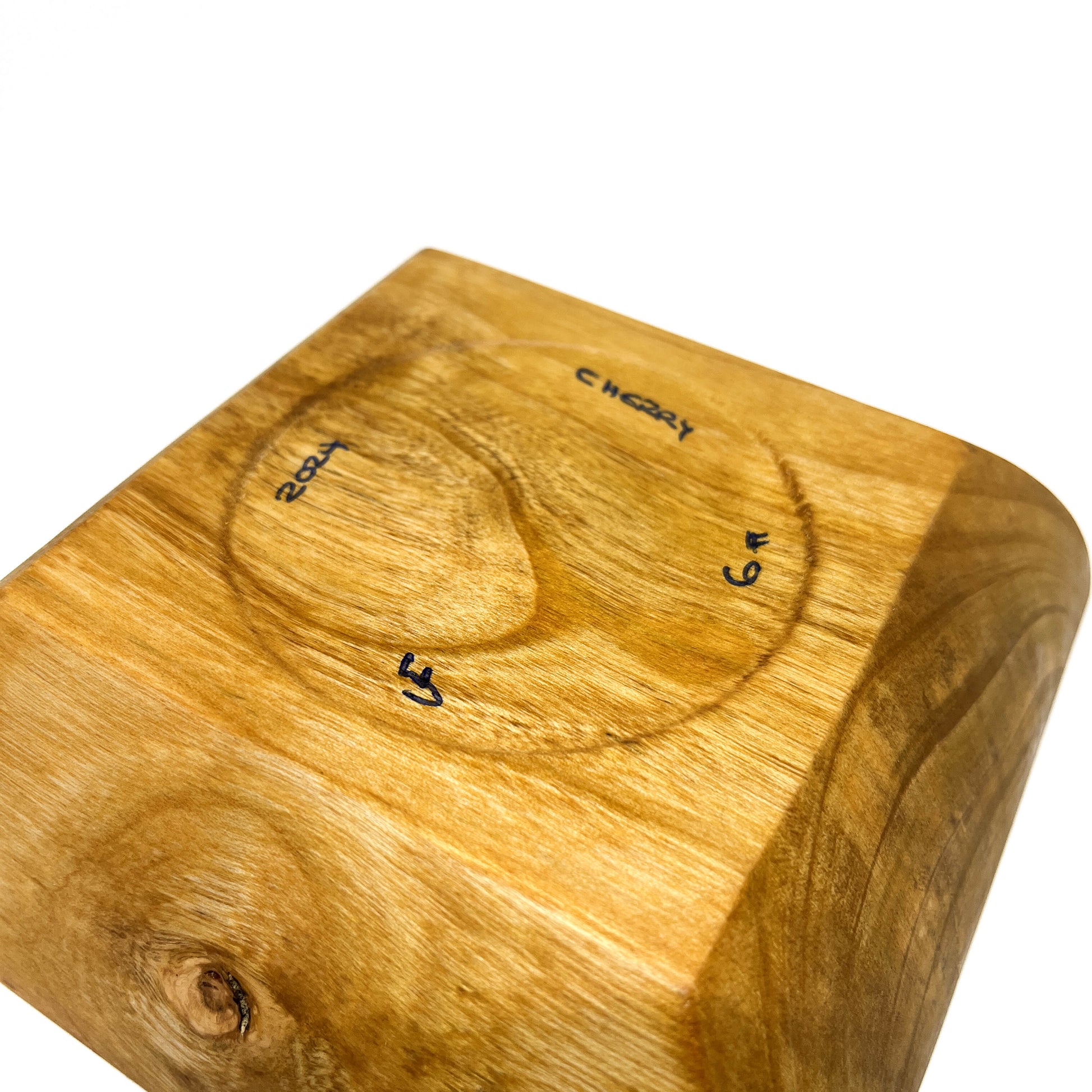 A close-up of the bottom of a square wooden bowl, showing markings.