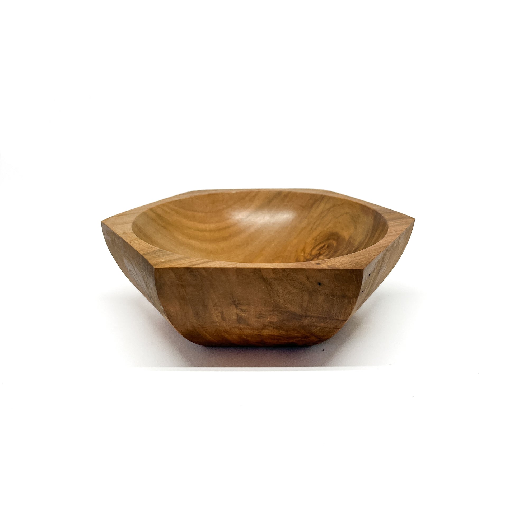 A six-sided wooden bowl with visible grain and a smooth, carved interior. The bowl has a shallow depth.