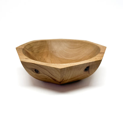 A light-colored, eight-sided wooden bowl with visible grain and a smooth, carved interior. The bowl has a shallow depth.