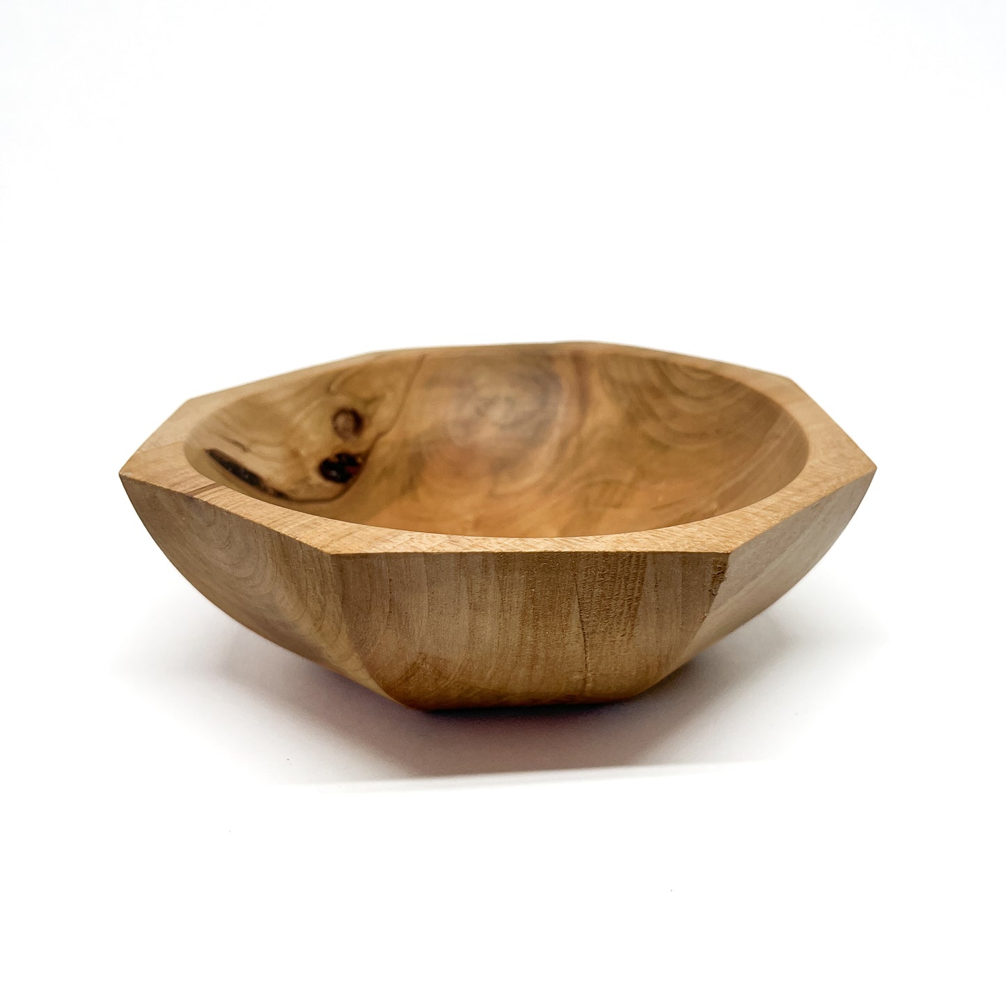 A light-colored, eight-sided wooden bowl with visible grain and a smooth, carved interior. The bowl has a shallow depth.