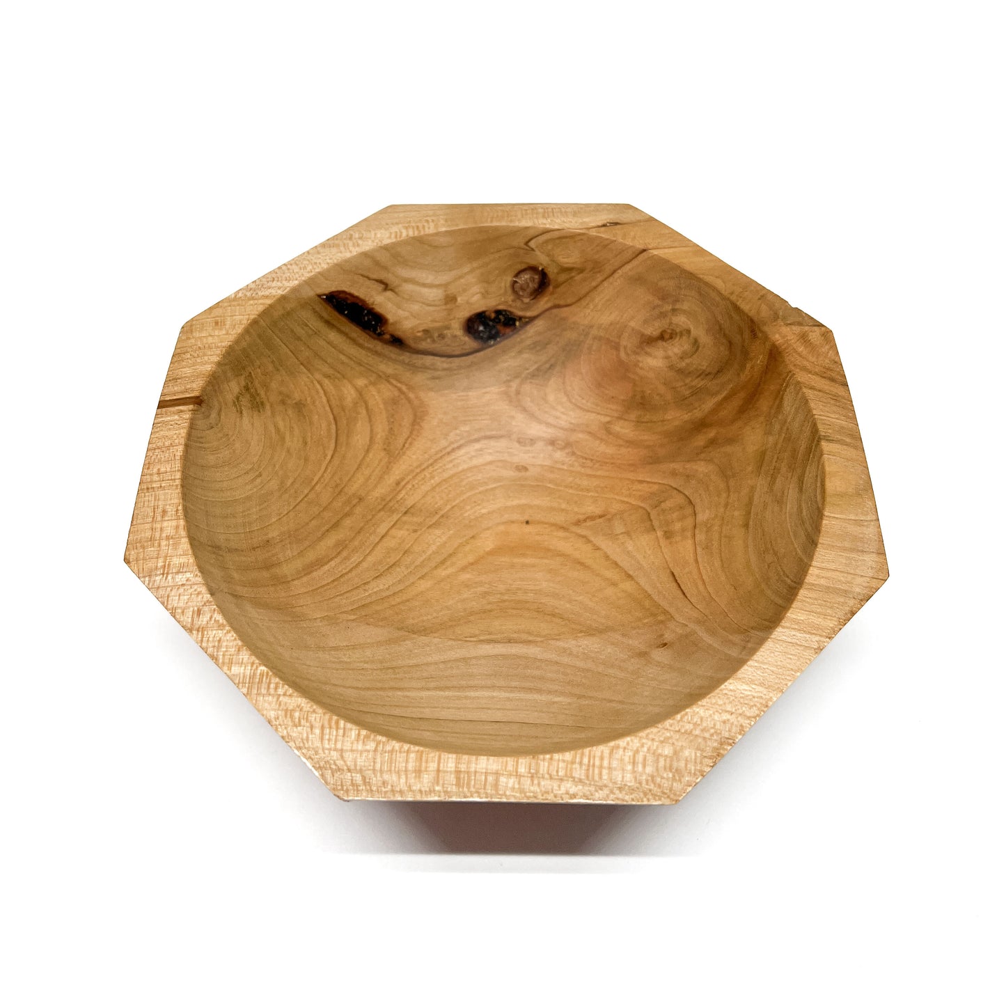 A light-colored, eight-sided wooden bowl with visible grain and a smooth, carved interior, viewed from above. The bowl has a shallow depth.
