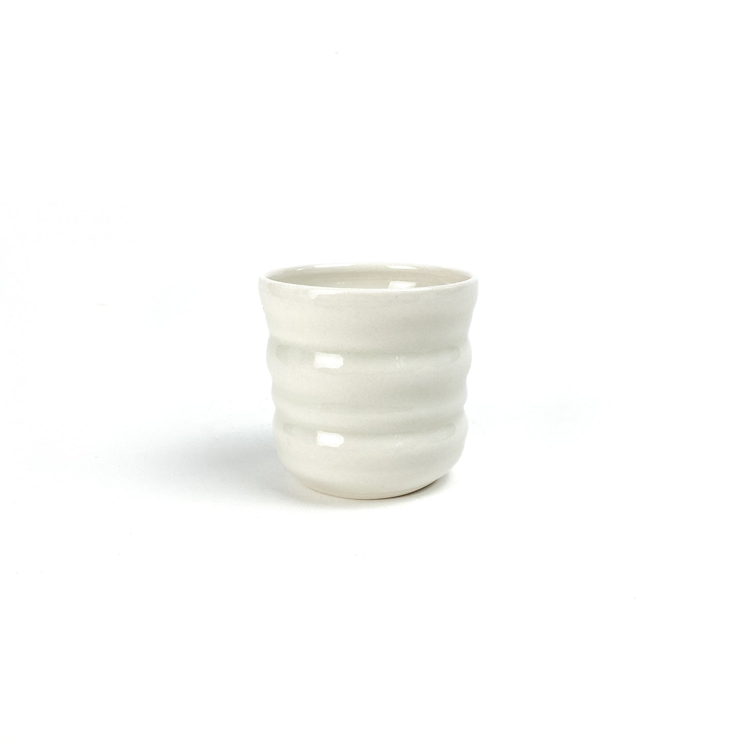 A small, cylindrical ceramic Yunomi cup with subtle horizontal ridges around its body.