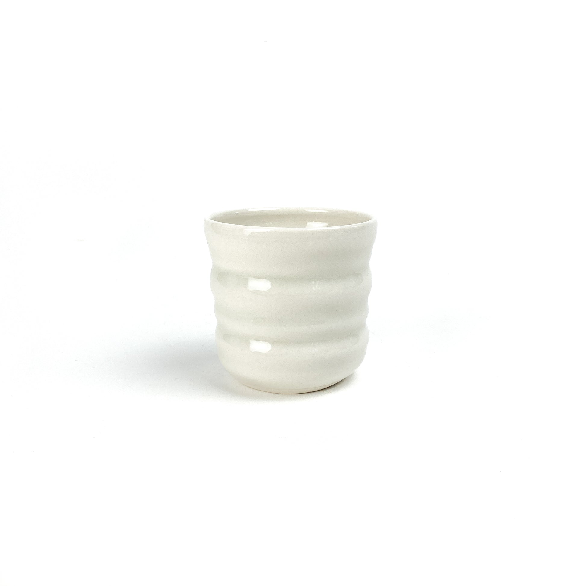 A small, cylindrical ceramic Yunomi cup with subtle horizontal ridges around its body.