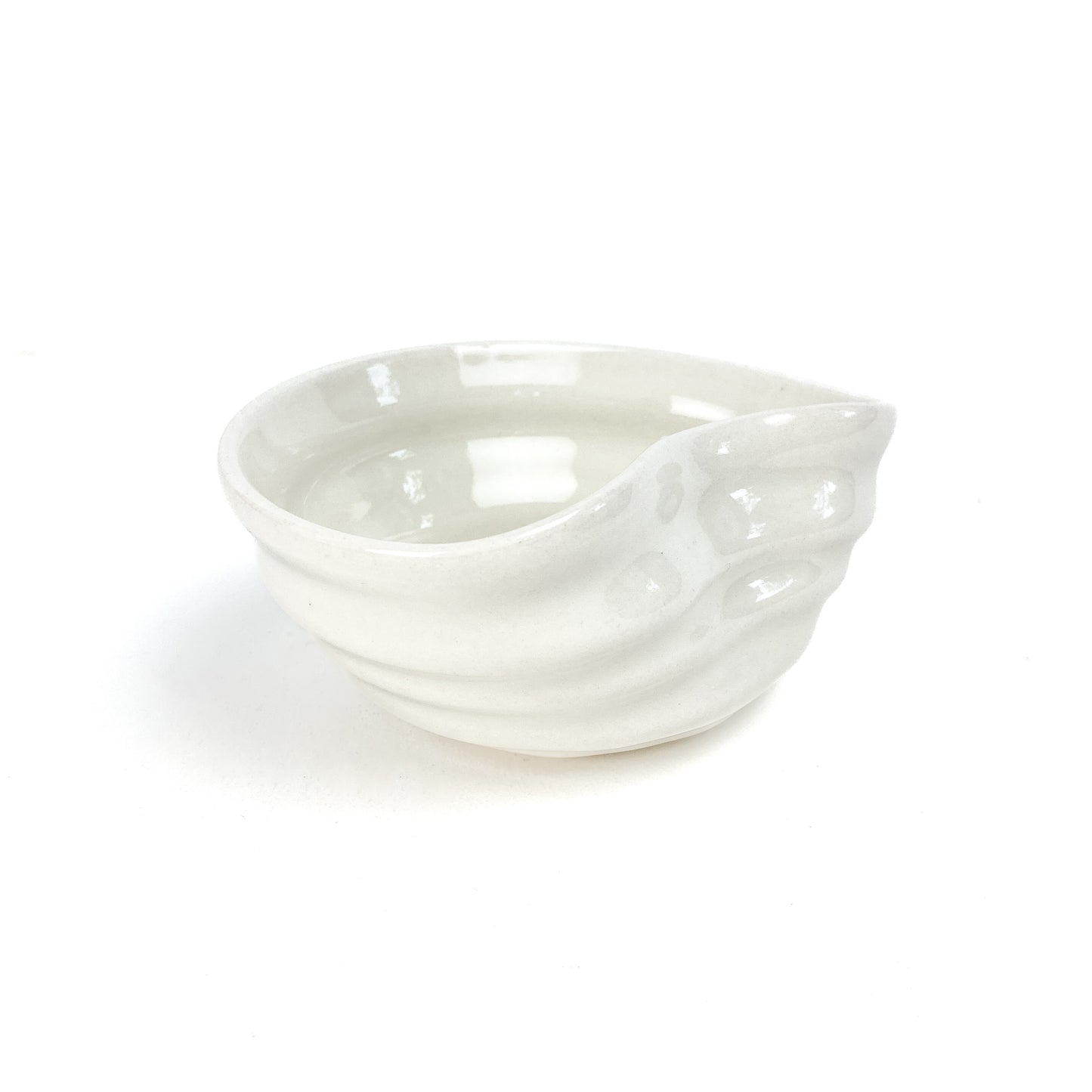 A small, light-toned ceramic concave bowl with textured, swirling ridges on its exterior.