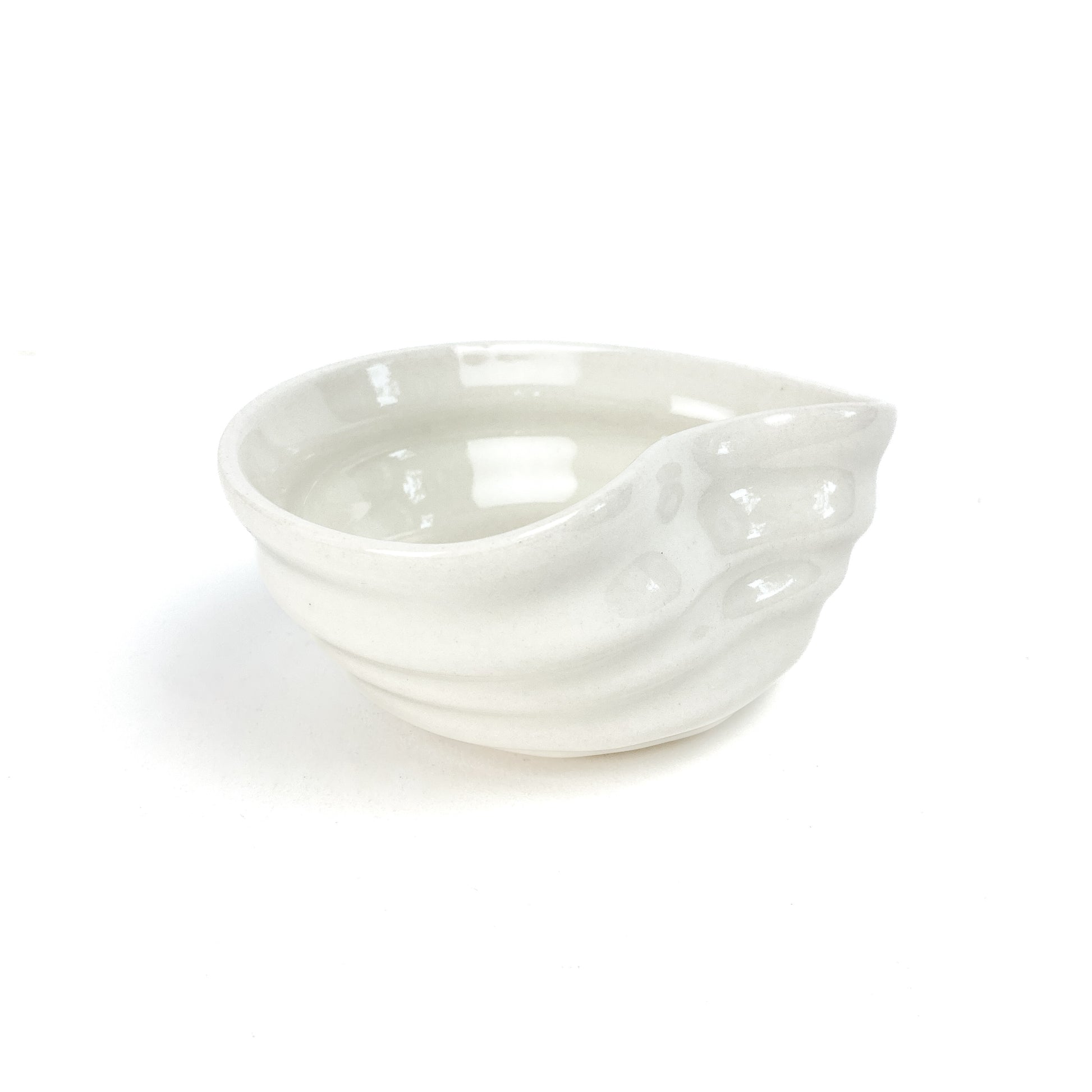 A small, light-toned ceramic concave bowl with textured, swirling ridges on its exterior.