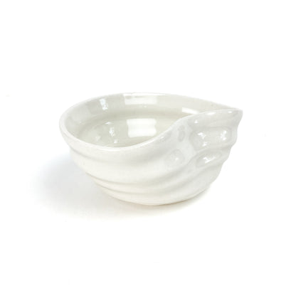 A small, light-toned ceramic concave bowl with textured, swirling ridges on its exterior.