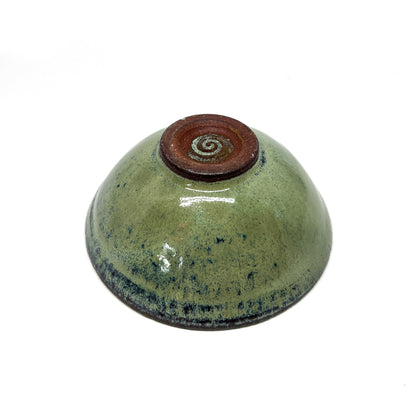 Underside of a green glazed terracotta bowl with a dark brown foot ring.