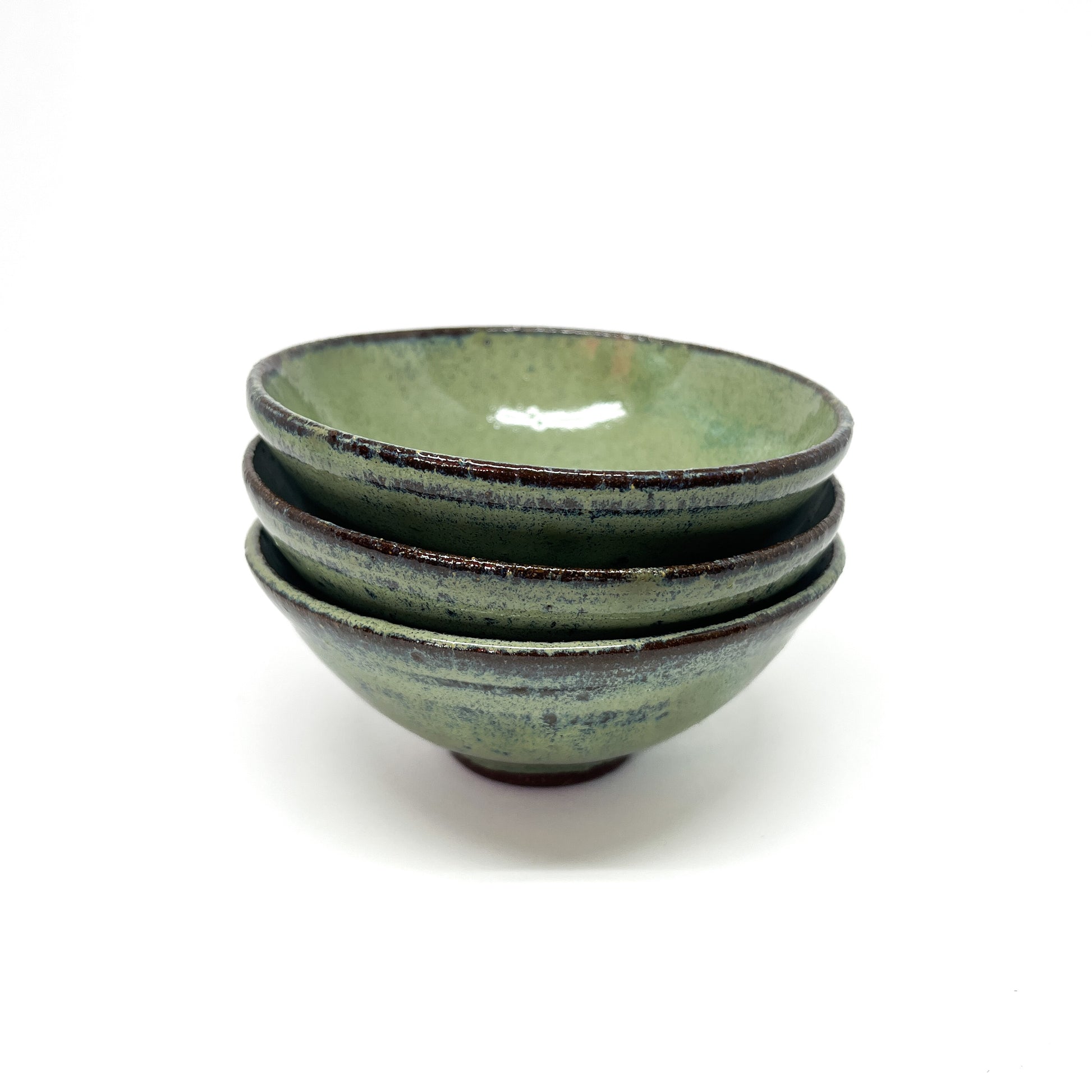 Stack of three green glazed terracotta bowls with dark rims.