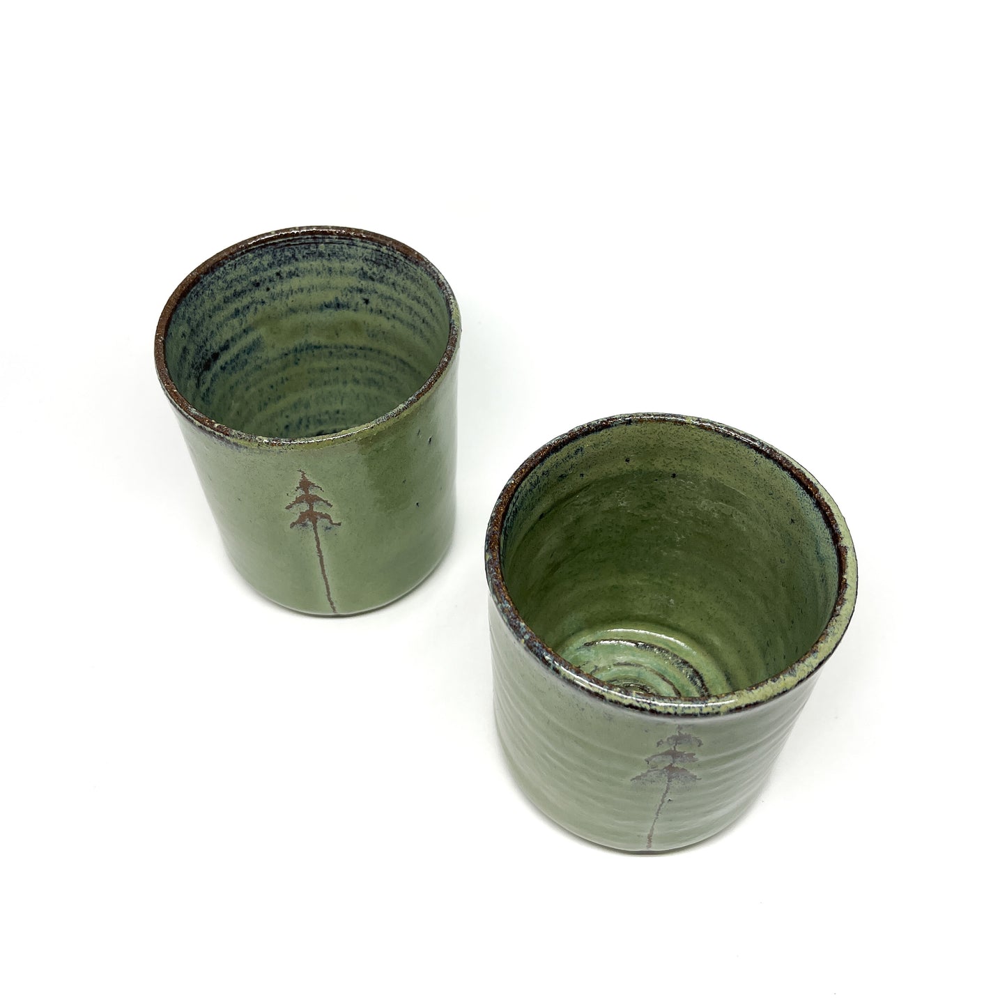 Two green ceramic cups with tree designs, top-down view.