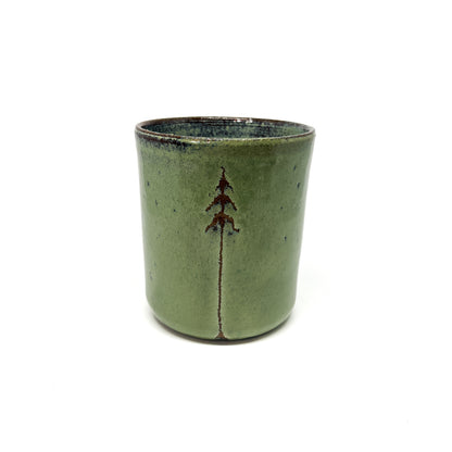 Green ceramic cup with a tree design, centered on a white background.