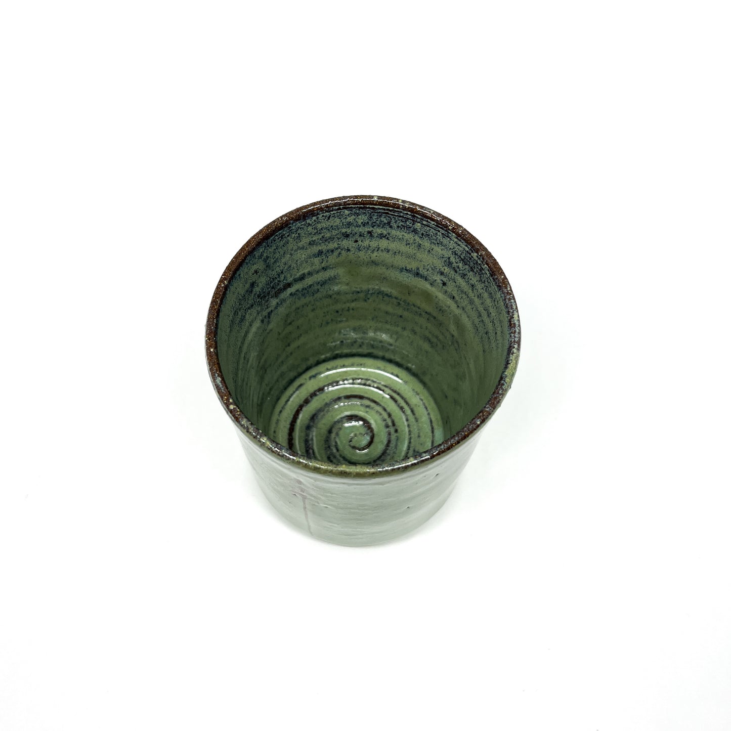 Green ceramic cup with a spiral design inside, top-down view on a white background.