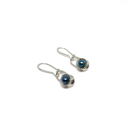 Two silver drop earrings with iridescent pearls in textured, scalloped settings.