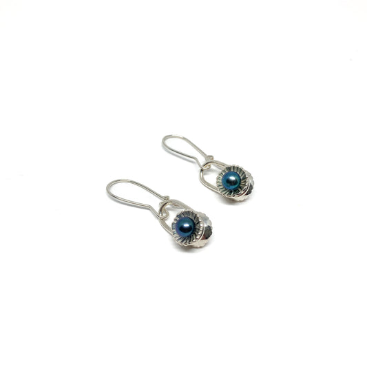 Two silver drop earrings with iridescent pearls in textured, scalloped settings.