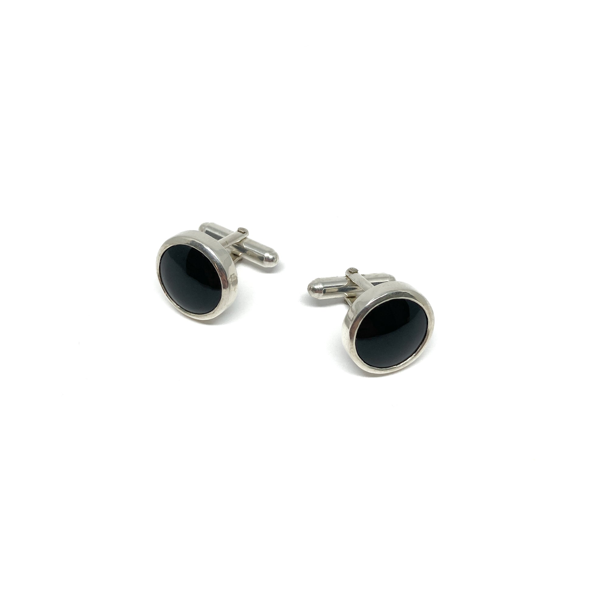 Two oval silver cufflinks, each featuring a polished black onyx gemstone setting.