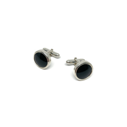 Two oval silver cufflinks, each featuring a polished black onyx gemstone setting.