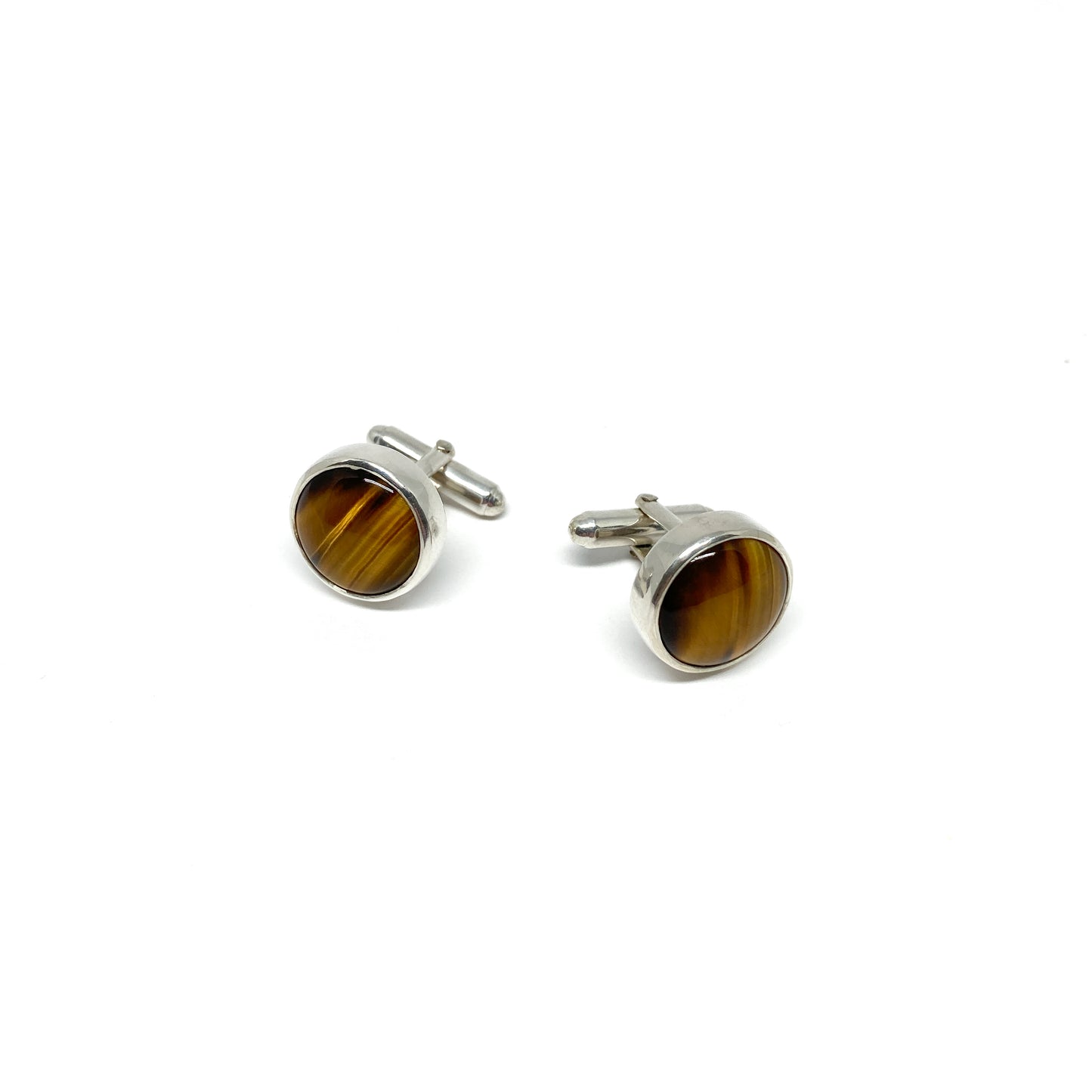 Two round silver cufflinks, each featuring a polished brown and gold gemstone.