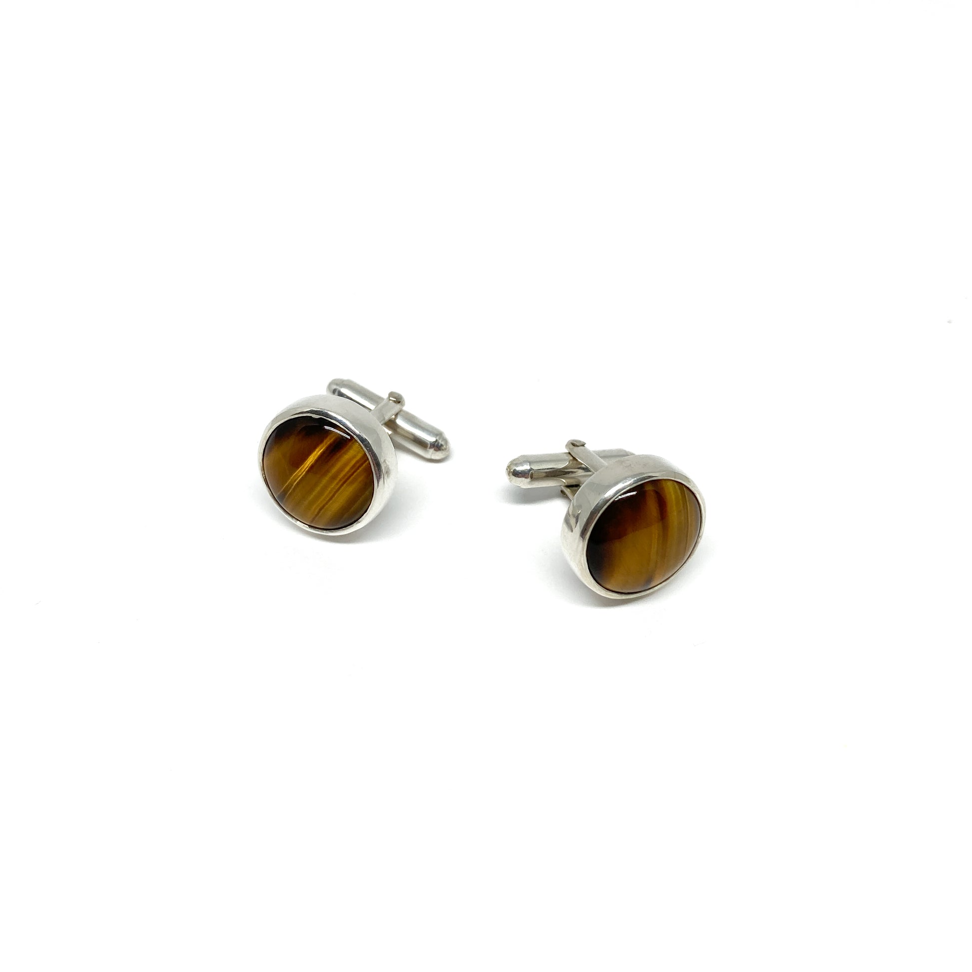 Two round silver cufflinks, each featuring a polished brown and gold gemstone.