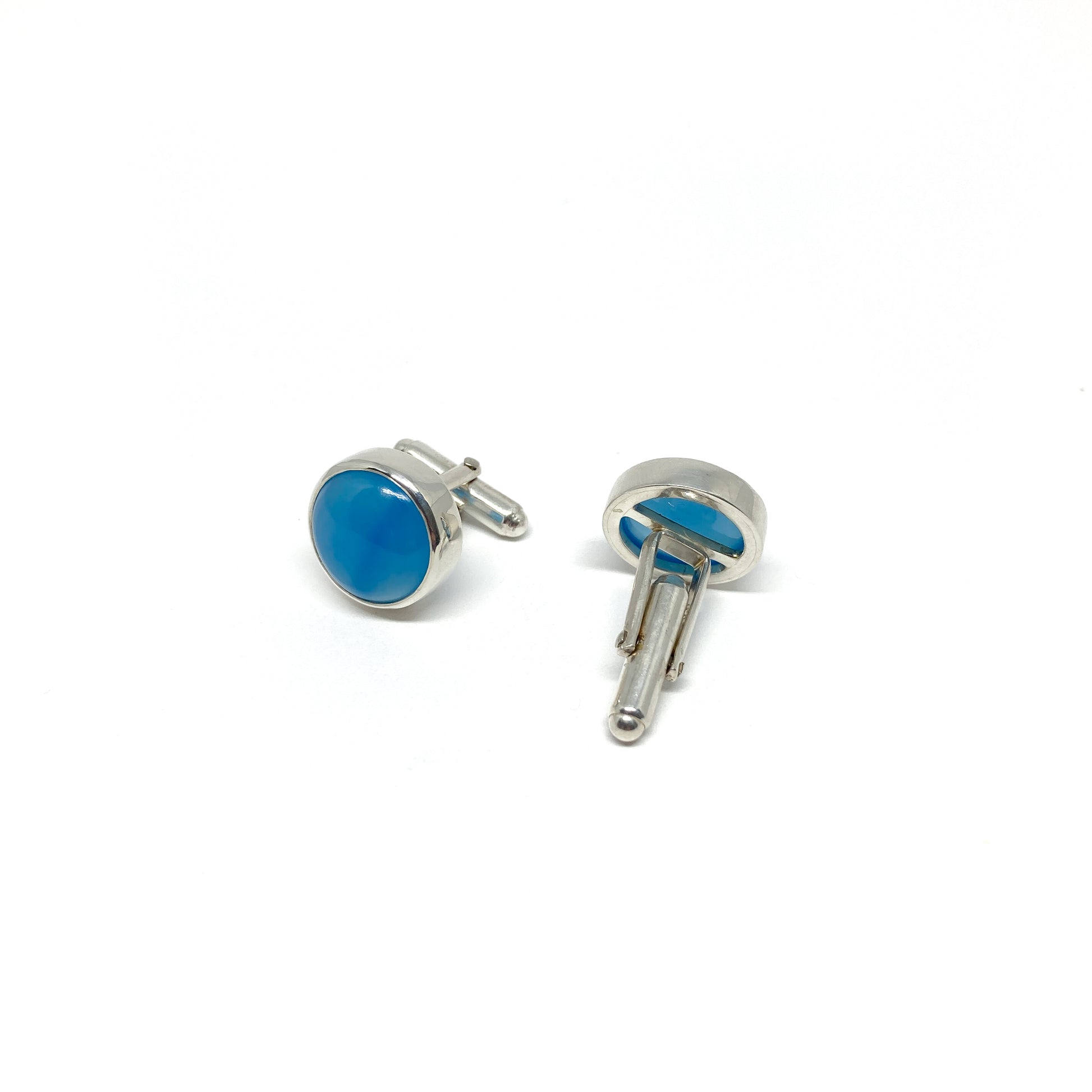 Pair of silver cufflinks with round, vibrant blue gemstone settings and toggle closures.