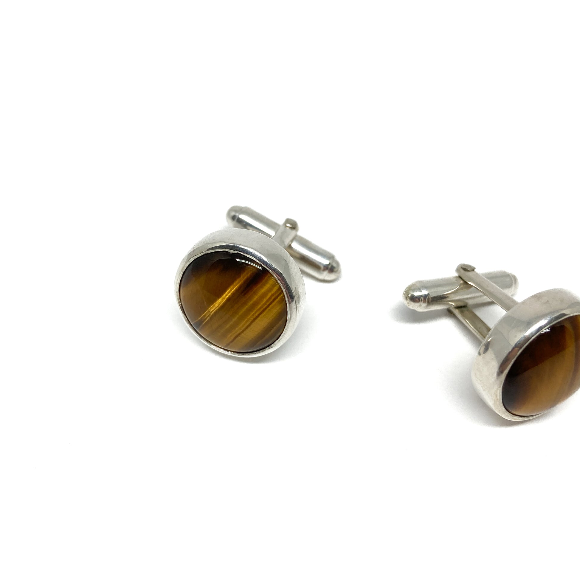 Pair of silver cufflinks with round, polished tiger's eye gemstones and toggle fastenings.