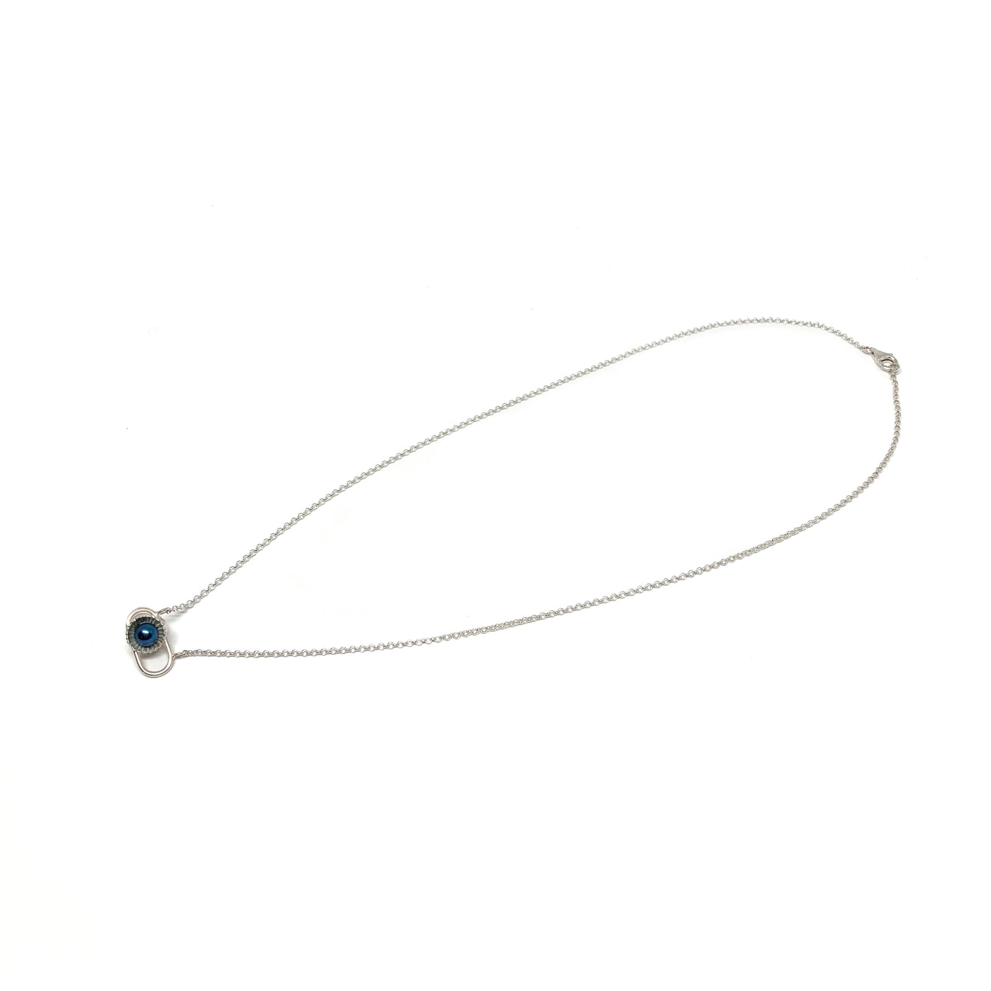 A delicate silver necklace with a small pendant featuring a dark, iridescent Taku Poe pearl in a textured setting.