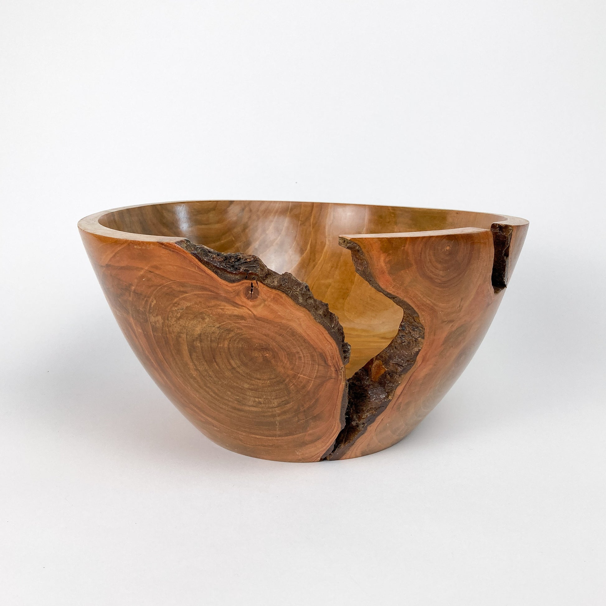 A wooden bowl with a natural crack and rough texture, showing the wood grain and a polished finish.