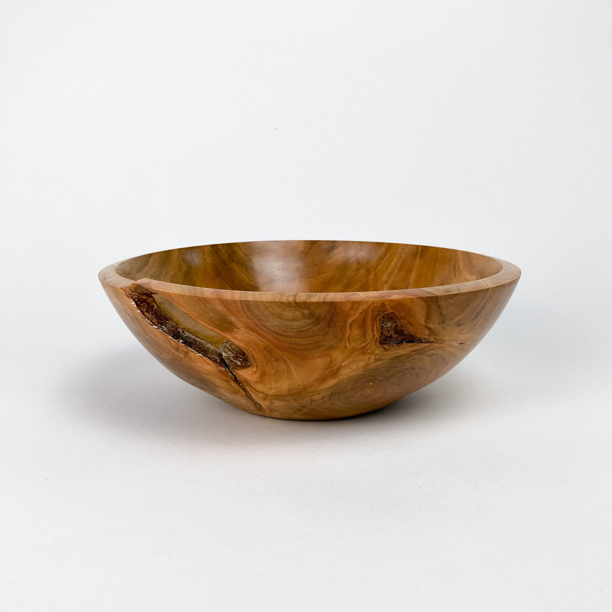 A wooden bowl with a smooth, polished finish, showing natural wood grain and a small crack.