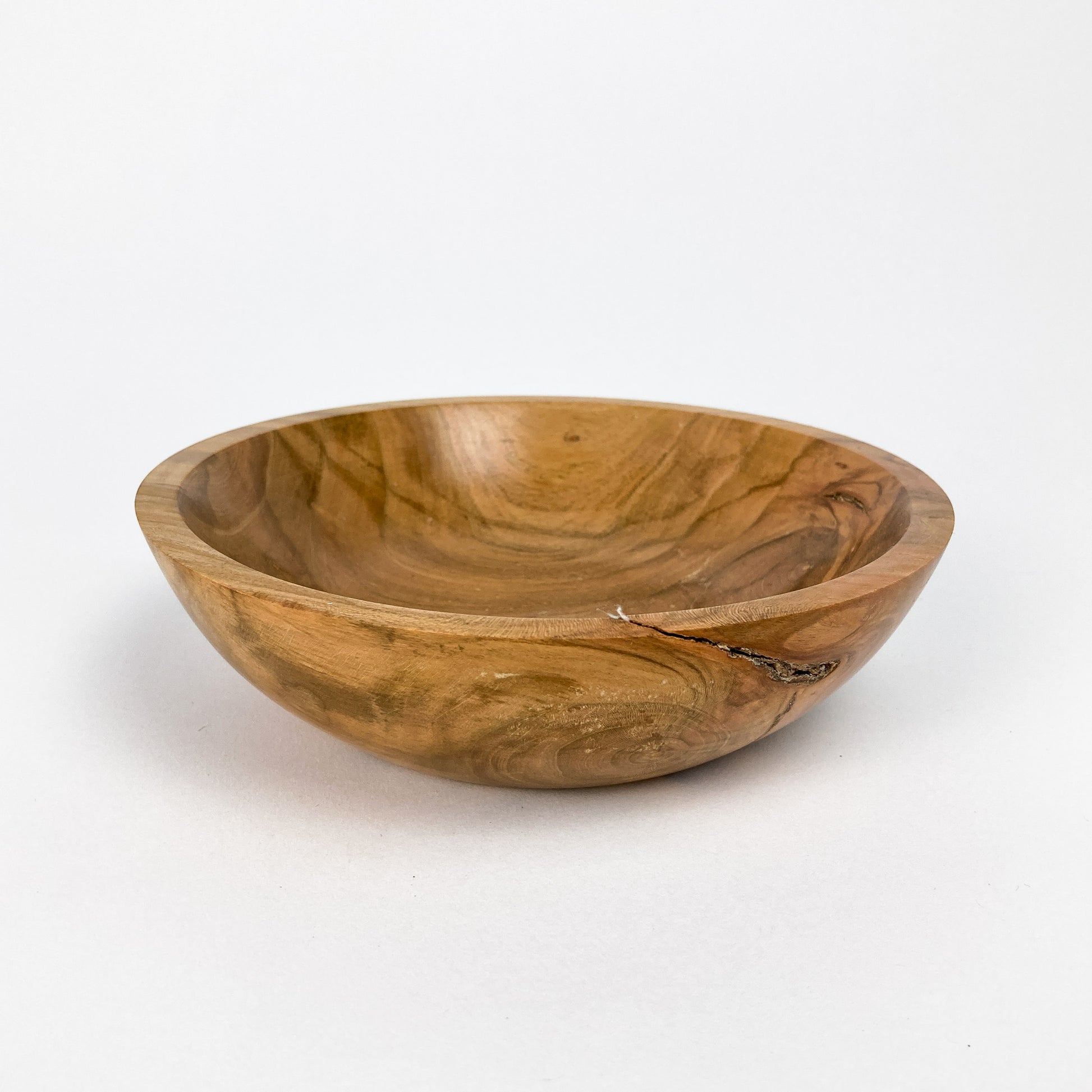 A small wooden bowl with a smooth, polished finish, showing natural wood grain and a small crack.