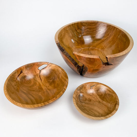 Three wooden bowls of different sizes, each with a smooth, polished finish and natural wood grain patterns.