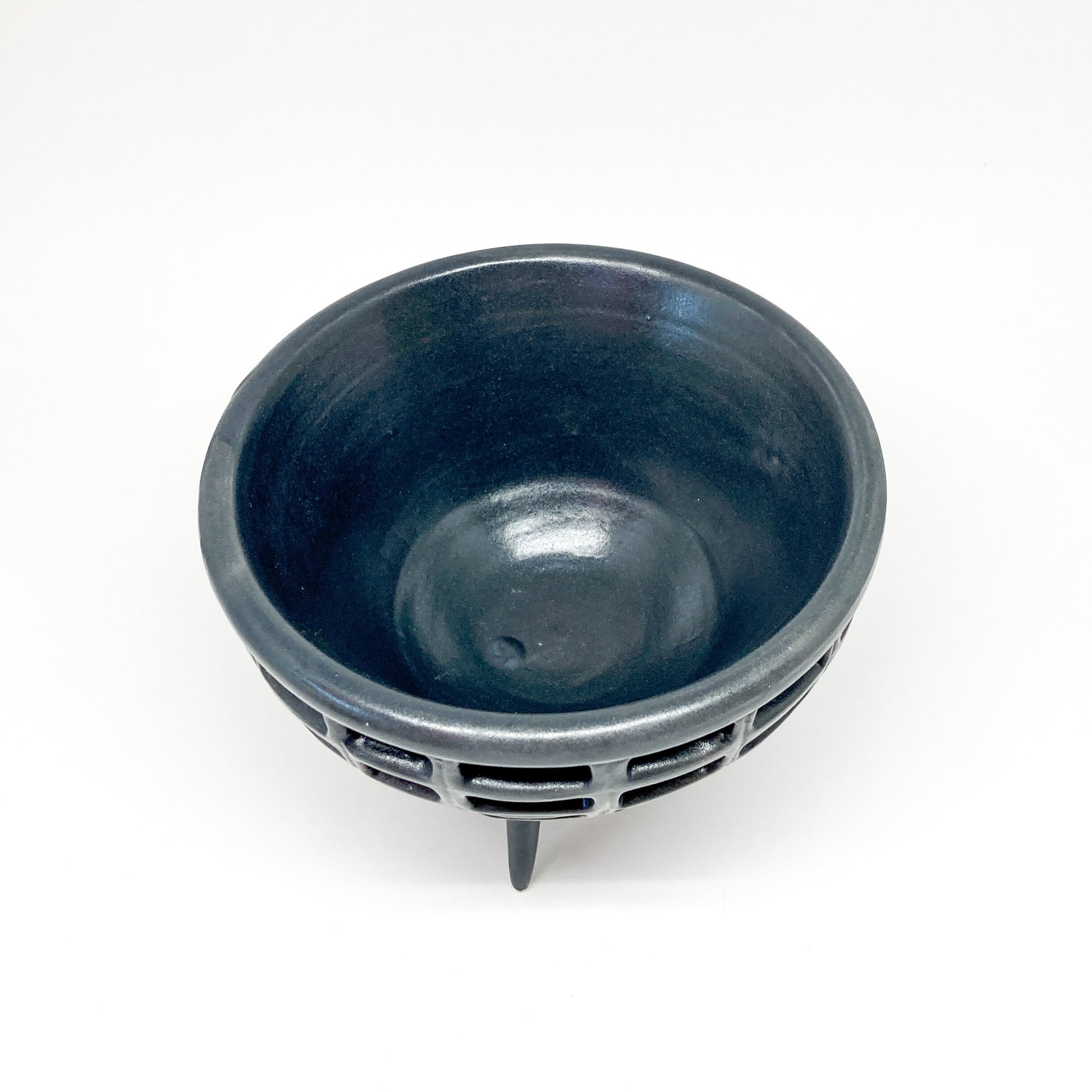 Top-down view of a black, double-walled diatom bowl showing its inner bowl and lattice outer layer. It rests on three small legs.