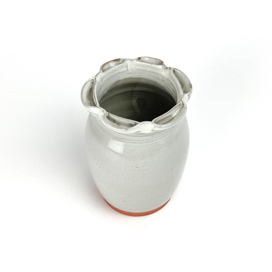 Top view of a Coral Patola Ripple Vase, a light-colored ceramic piece with a rippled rim and unglazed base.