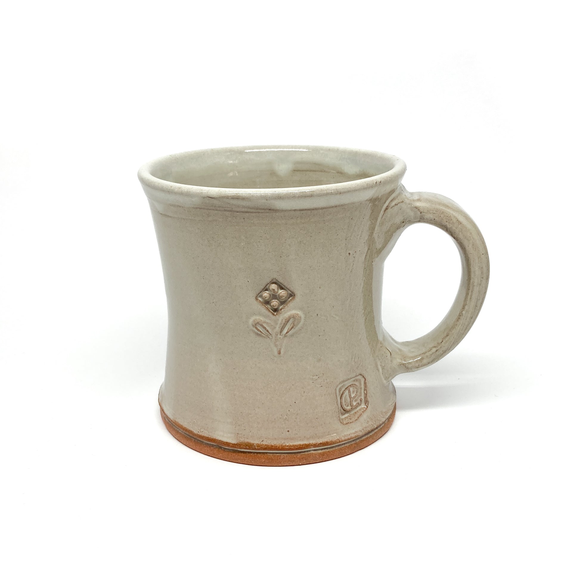 Speckled, glazed ceramic mug with a small, embossed floral design and a maker's mark near the base.
