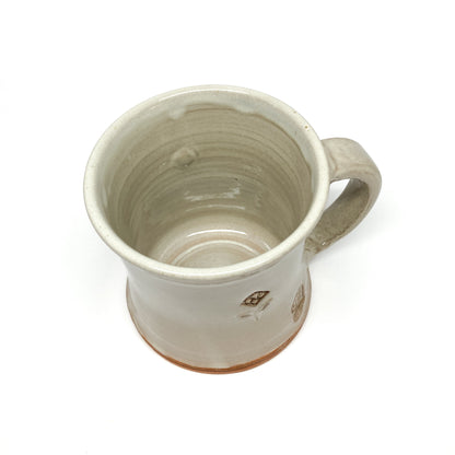 Overhead view of a speckled, glazed ceramic mug with an embossed floral design and maker's mark.
