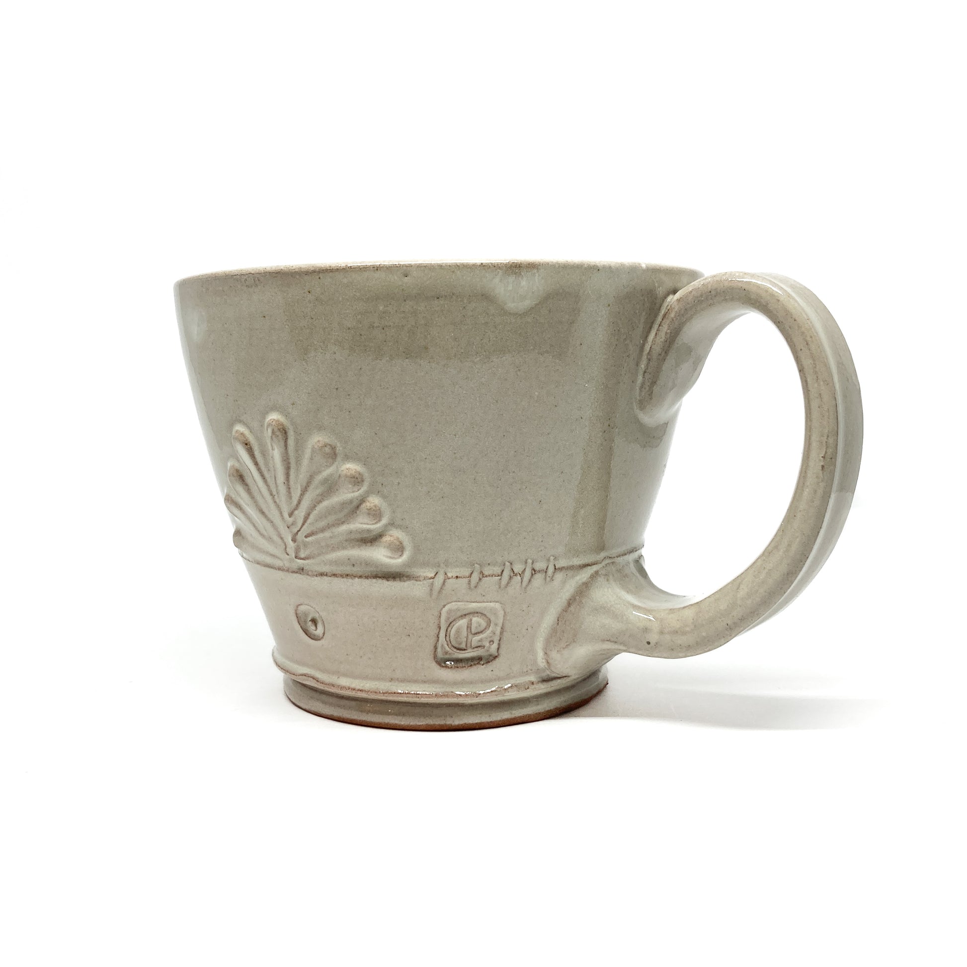 Speckled, glazed ceramic latte mug with an embossed, stylized floral design and a circular maker's mark.
