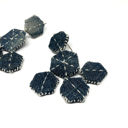 Close-up of one "Patched Chandelier" earring showing layered denim hexagons with white stitching.